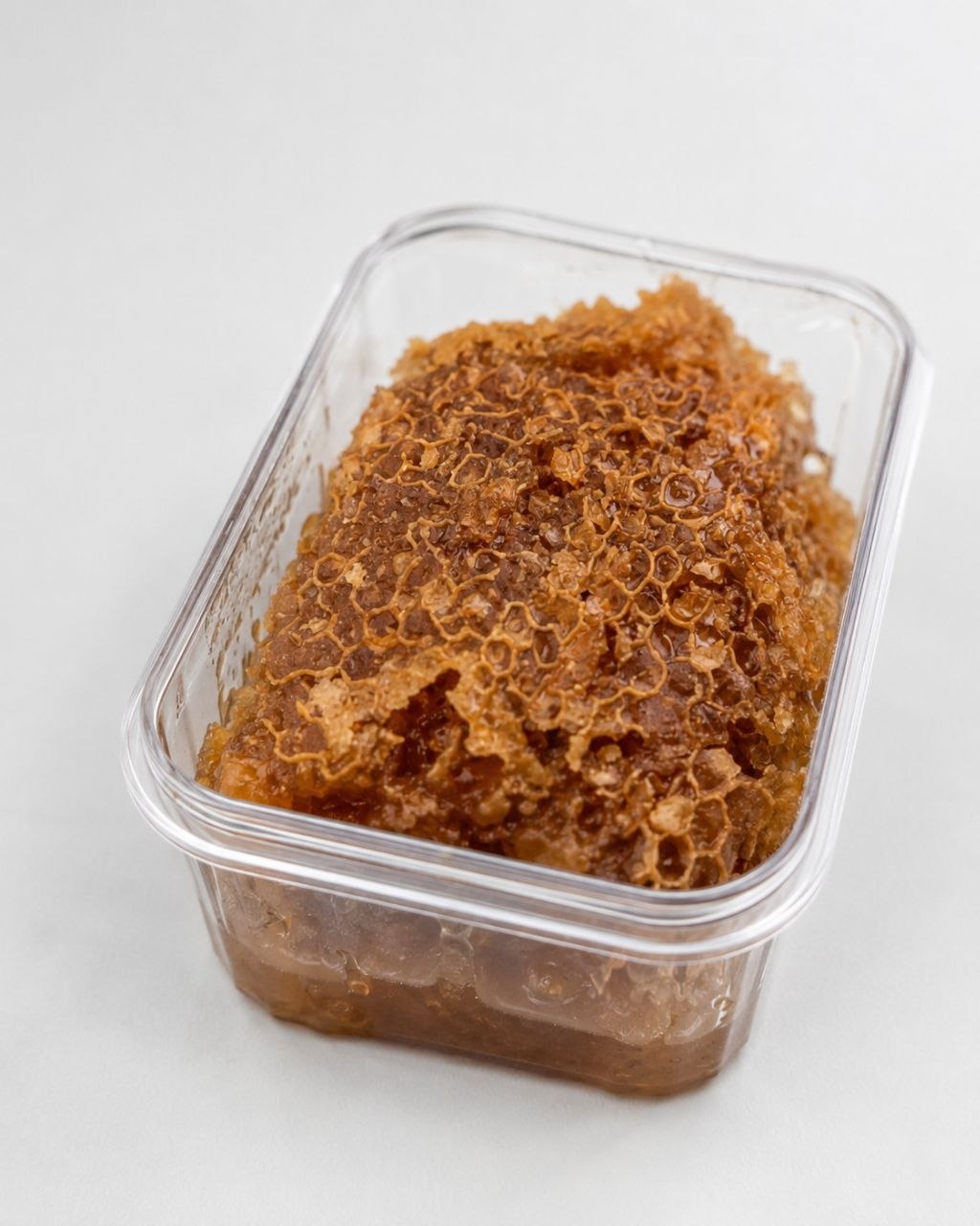 Close-up of BEEZY raw honeycomb in a clear container